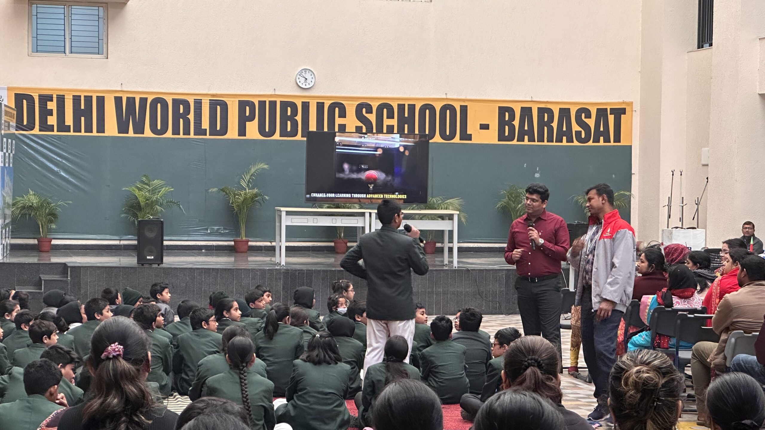 School ground area with a stage in front where children are interacting as an activity is ongoing